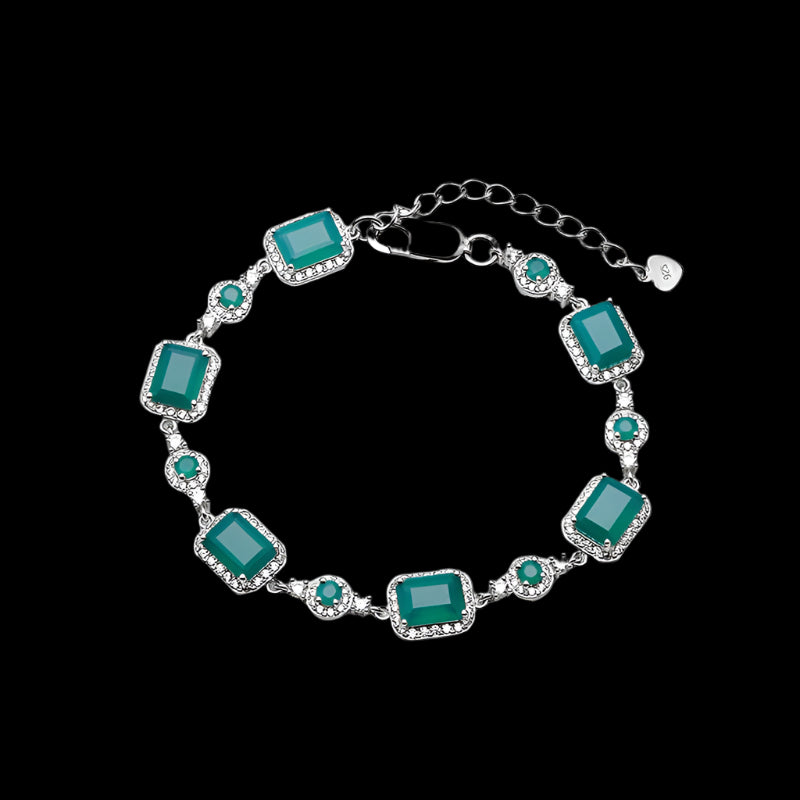 Silver bracelet with green gemstones on a white background