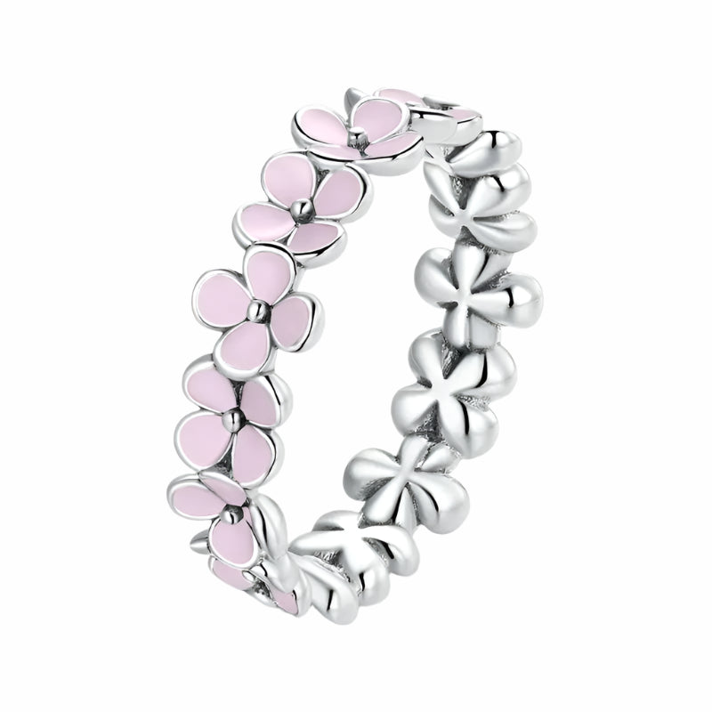 A silver ring with pink accents, featuring a floral pattern in a twisted metal design.