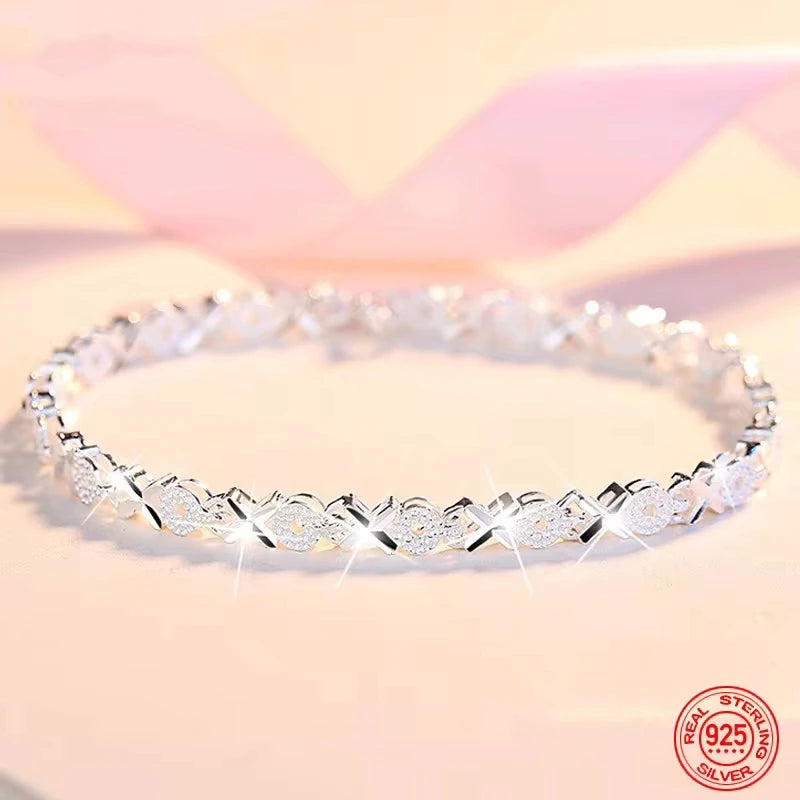 A sterling silver bracelet with a geometric pattern and multiple rows of small stones set along its length.