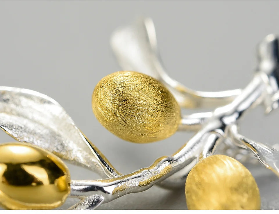Silver and gold jewelry piece on a gray background