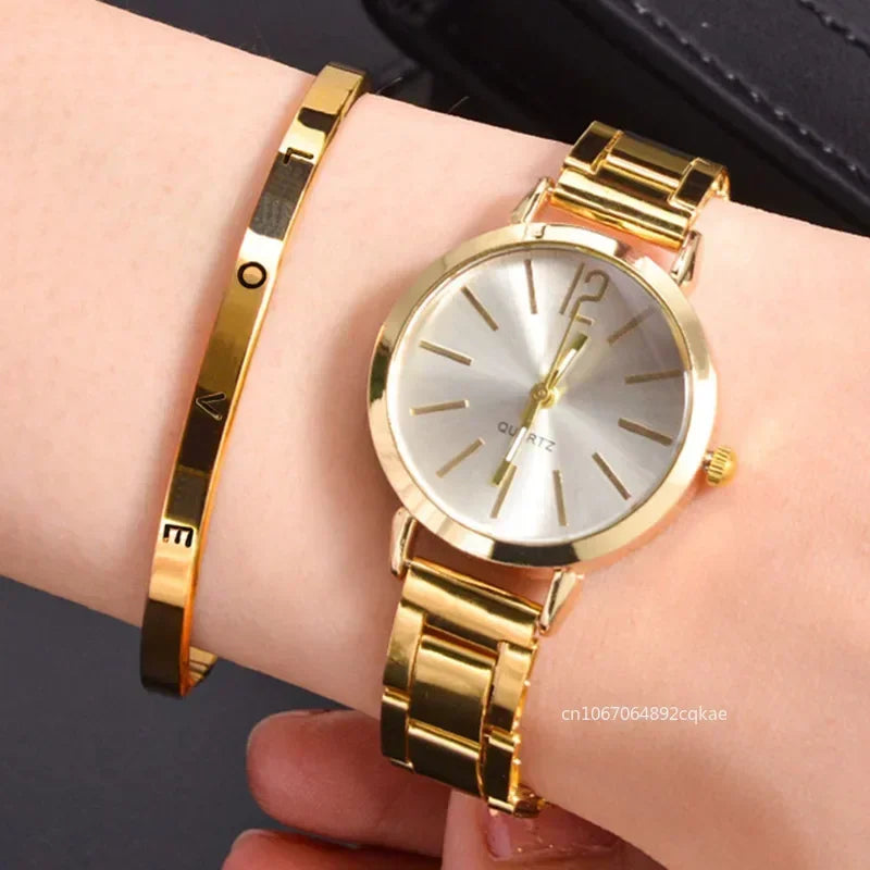 A gold-colored analog-digital watch with a metallic band, displayed on a person's wrist alongside a gold-colored bracelet.