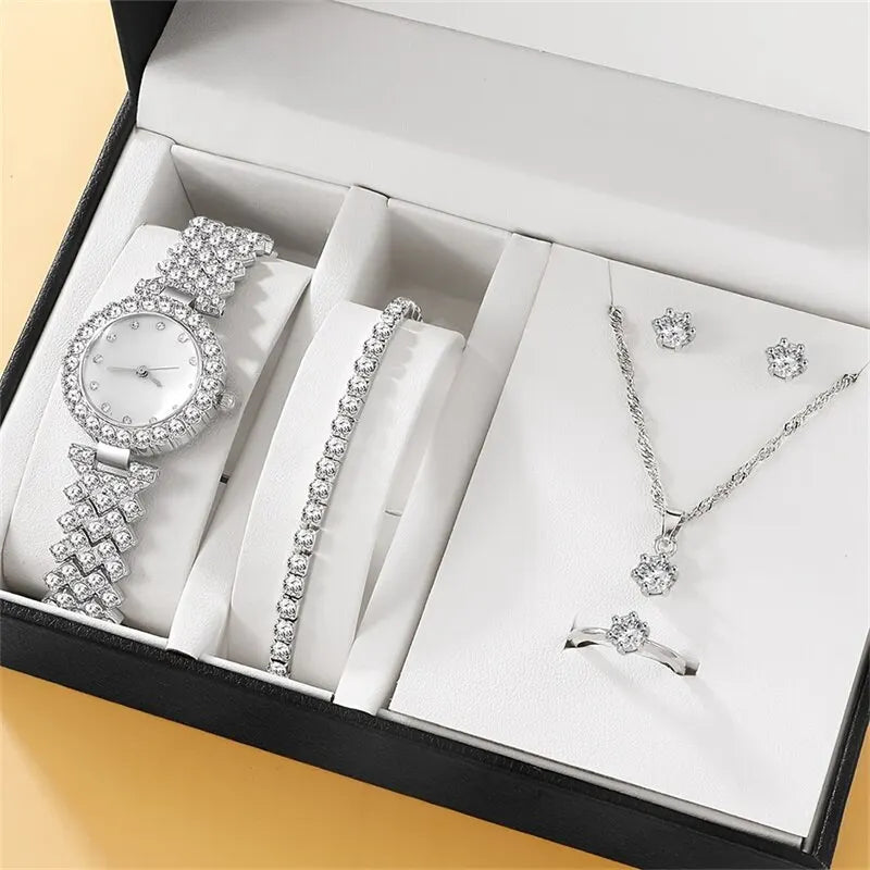 A set of jewelry including a watch, bracelet, necklace, and earrings with a silver finish displayed in an open box.