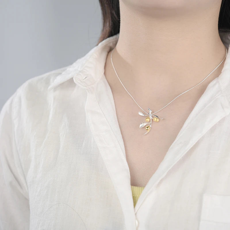 Necklace with a dragonfly pendant worn by a person in a white shirt.
