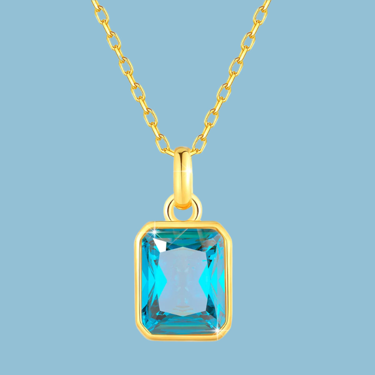 Gold necklace with a blue gemstone pendant on a white background