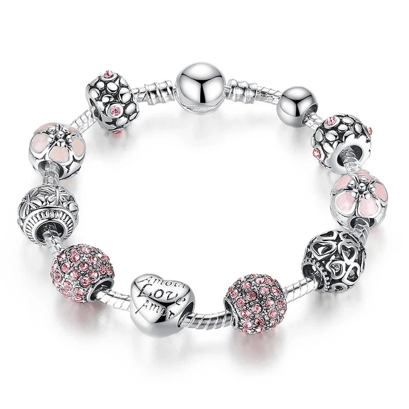 A silver-plated snake chain bracelet with various charms including heart-shaped and floral designs, adorned with crystals and metallic elements.