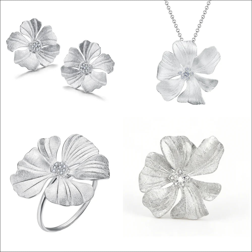 Four-piece silver jewelry set featuring a flower pendant necklace, matching stud earrings, a flower ring, and a larger flower brooch, all with textured petals and small clear crystal centers, displayed on a white background